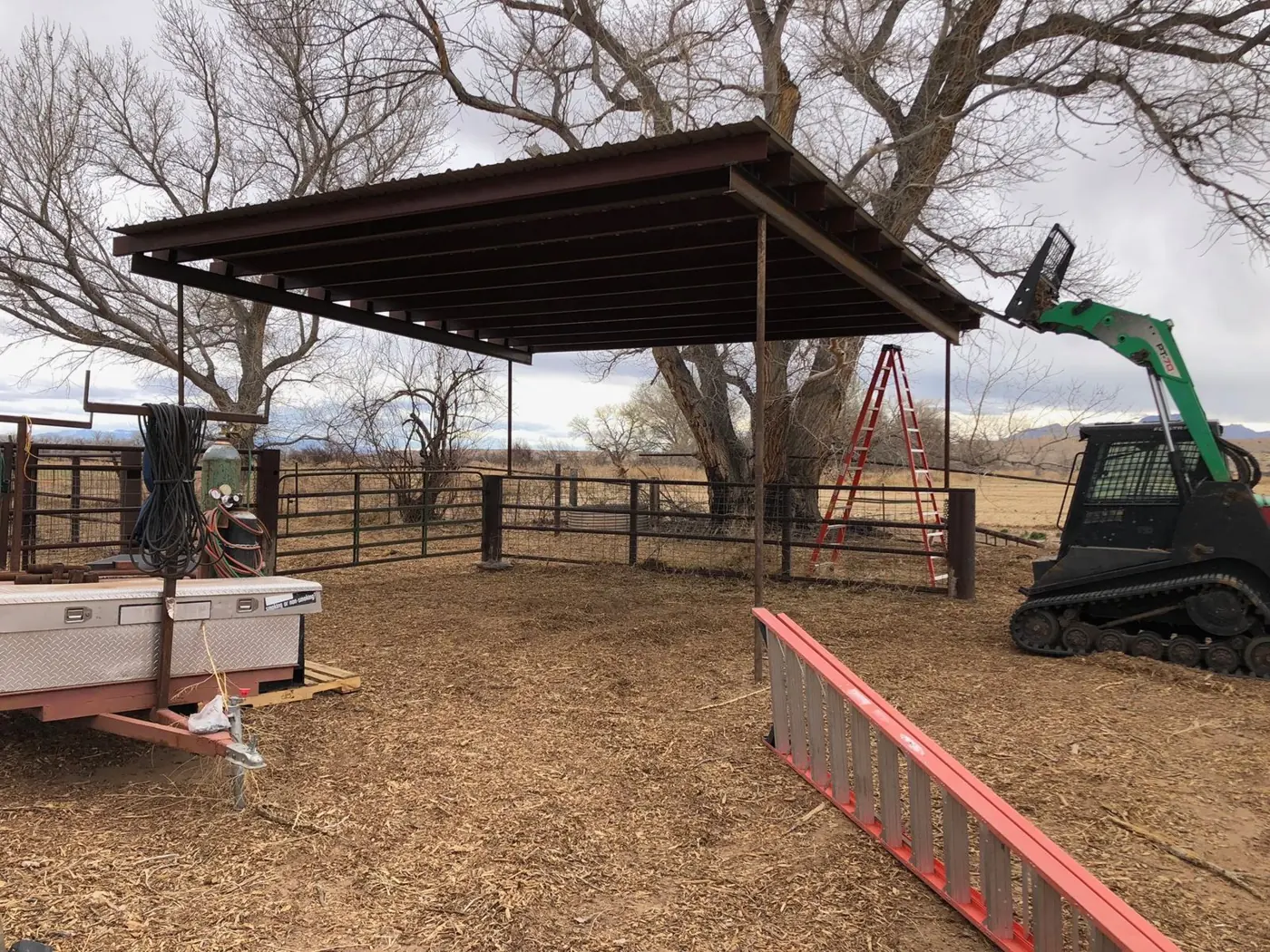 Steel shade structure with a metal roof over a pipe corral